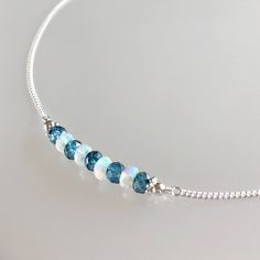 Genuine welo opal and london blue topaz bar choker/necklace in sterling silver This necklace features genuine ethiopian opals and london blue topaz gemstones arranged in a bar that is wire-wrapped to a delicate but sturdy sterling silver chain; secured with a lobster claw clasp.  The beaded bar is designed with a slight curve for a smooth drape and perfect fit.  The london blue topaz are permanently coated white topaz beads. An elegantly subtle necklace that can easily be worn by itself or paired with others for a layered look.  Details: necklace length: please choose desired length at check-out london blue topaz: approx. 4 mm welo opal: approx. 3.5 - 4 mm sterling silver chain and other components Thanks for visiting ! Back to my shop for more jewelry options: www.etsy.com/shop/krisatdesi Cheap White Christmas Necklace, Cheap Blue Beaded Necklace For Gift, Cheap Elegant Sterling Silver Beaded Necklaces, Cheap Blue Chain Jewelry, Cheap Blue Beaded Necklace For Gifting, Opal Bar Necklace, London Blue Topaz Necklace, Blue Topaz Necklace, Garnet Bracelet