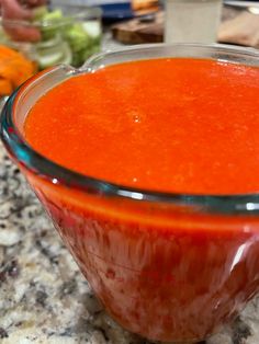 a glass bowl filled with red sauce on top of a counter