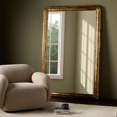 a chair sitting in front of a large mirror on top of a wooden floor next to a window