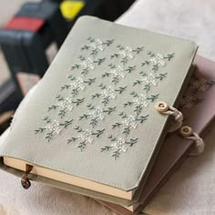 two books with embroidered designs on them sitting on a table next to some other items