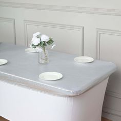 a vase with white flowers sitting on top of a table next to two empty plates