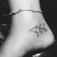 a black and white photo of a world map tattoo on the side of a foot