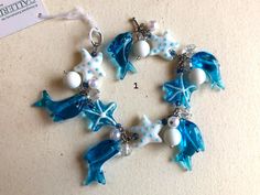 "The Perfect Fun Tropical Beachy Gift : This silver chain is loaded with glass fish ornaments, starfish, shells, dolphins pearls and more. I The bracelet is 7-1/2\" long not including the clasp. There are 3 different styles to choose from. These are made with lamp-glass beadings & faux pearls with lots of hanging tropical ornaments. They were made by \"Gallerie II\" designs and i used them ornaments for decorations on children's chandeliers. I no longer need them and have a few left;, they a Unique Starfish Charm Jewelry As Gift, Unique Jewelry With Starfish Charm As Gift, Starfish Charm Bracelet Gift, Starfish Charm Bracelet As A Gift, Turquoise Bracelet With Starfish Charm As Gift, Ocean-inspired Blue Charm Bracelet For Gifts, Ocean-inspired Starfish Bracelets As Gifts, Ocean-inspired Bracelet Jewelry Gift, White Starfish Charm Bracelet