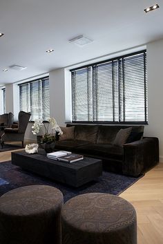 a living room filled with furniture and windows covered in shades of blue, brown and white