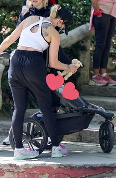 a woman pushing a stroller with a heart cut out on the back of it