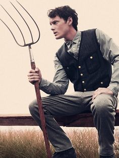 a man sitting on a bench holding a pitchfork