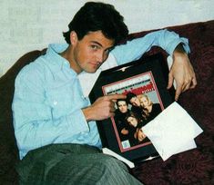 a man sitting on top of a couch holding a framed photo