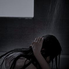 a woman standing in the rain with her hands on her head and water pouring over her face