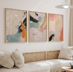 three paintings hang on the wall above a couch