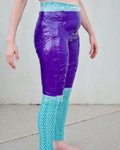 a woman wearing purple and blue leggings standing on concrete