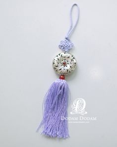 a tasseled keychain with a medallion and beads hanging from it's side