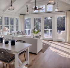 a living room filled with white furniture and lots of windows next to a wooden floor