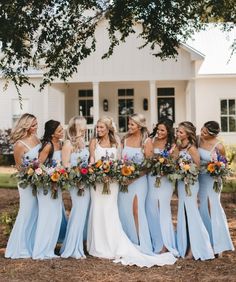 a group of women standing next to each other in front of a house with flowers