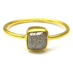 a gold and silver ring with a square stone on the front, sitting on a white surface