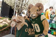 a man in a ram costume walking down the street with a goat on his back