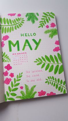 an open notebook with the words hello may written in green and pink flowers on it