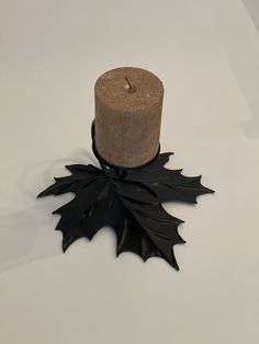 a candle that is sitting on top of a wooden table with a leaf decoration around it