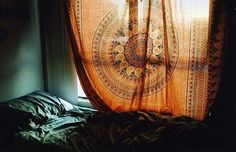 the sun shines through an open window onto a bed in front of a curtain