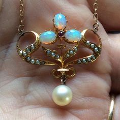 Stunning antique fiery opal ruby seed pearls and pearl dropper necklace set in gold, dating from the 1900’s.Here we have a a lovely necklace set in a warm buttery gold, and set with three fiery opals in the shape of a flower, and with a central faceted ruby. The leaves of the flower are inlaid with lustrous creamy seed pearls. At the base of the flower is a lustrous large creamy cultured pearl drop.The fiery opals range is colour from a fabulous green, with flashes of blue, and orange.The neckla Vintage Gold Opal Jewelry, Victorian Cabochon Necklace For Wedding, Antique Cabochon Necklaces For Wedding, Vintage Opal Gemstone Jewelry, Antique Gold Opal Jewelry, Antique Opal Jewelry In Gold, Victorian Opal Jewelry For Formal Occasions, Victorian Pendant Jewelry For Opera, Vintage Opal Jewelry In Yellow Gold