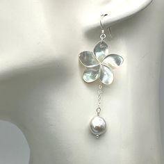 These earrings are a simple but elegant look with a lustrous carved white mother of pearl flower accented with a single iridescent freshwater teardrop pearl. There are beautiful tones of light pink and silver in the pearl and flower. The earrings are made with delicate sterling silver chain and have the option of sterling silver wires or posts. The dangle be made in different lengths. The flower is approximately one inch in size. The chain and pearl hand down approximately 2 inches from the top of the flower to the bottom of the pearl. This length can be adjusted if needed with a message. There is a matching necklace at the following link, https://www.etsy.com/listing/1381620161/white-mother-of-pearl-plumeria-y?click_key=ec3549c602273ca491c282ce2a7f50de06af13fe%3A1381620161&click_sum=c7605 Elegant Nickel-free Shell Earrings, Beach Wedding Earrings, Nickel-free White Shell-shaped Earrings, Luxury Flower-shaped Mother Of Pearl Earrings, Elegant Shell-shaped Mother Of Pearl Earrings, Silver Shell-shaped Earrings With Pearl Drop, Pearl Flower, Matching Necklaces, Wedding Earrings