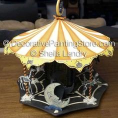 an old fashioned carousel on a wooden floor with a yellow and white striped umbrella over it