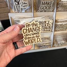 a person holding up a sticker that says be the change you want to see in the world