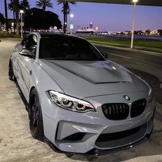 a silver car parked on the side of a road next to palm trees at night