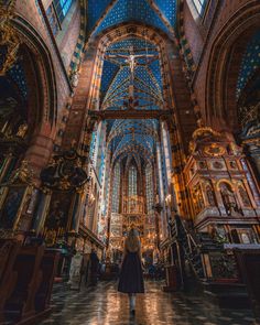 a woman standing in the middle of a church looking up at the ceiling and stained glass windows