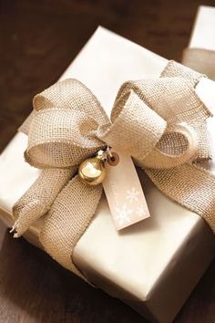 a present wrapped in burlap with a bell on it's bow and tag