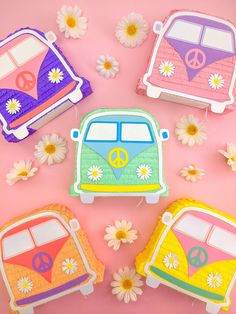 three decorated cookies sitting on top of a pink surface next to daisies and flowers