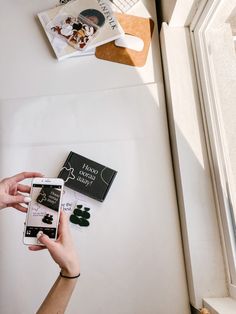 a person holding an iphone in front of a table with books and other items on it