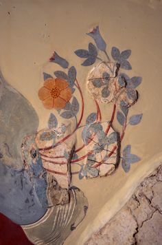 an artistic painting on the side of a wall with flowers and leaves painted on it