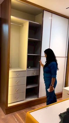 a woman is standing in front of a closet with drawers and shelving units on the wall