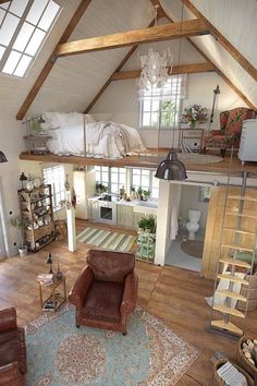 an aerial view of a living room and kitchen area with wood floors, exposed beams, vaulted ceiling, and leather chairs