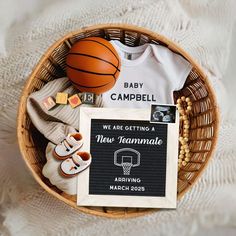 a basket filled with baby items including shoes, socks and a t - shirt that says we are getting a new team mate