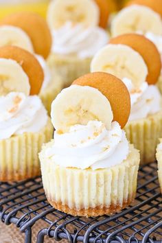 cupcakes with banana slices and whipped cream frosting are on a cooling rack