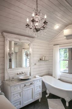 a bathroom with a claw foot tub and chandelier