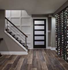 a wine cellar in the middle of a room next to a stair case filled with bottles