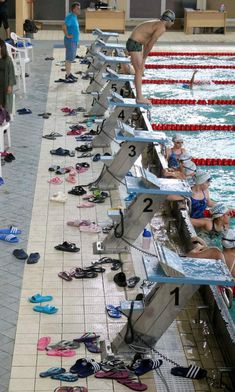 several swimmers are lined up at the edge of an indoor swimming pool