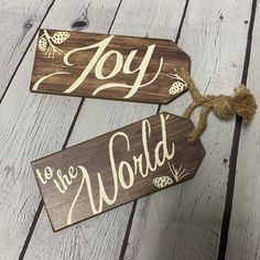 two wooden signs with the words joy to the world and pinecone on them