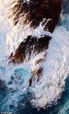 an aerial view of the ocean and rocks