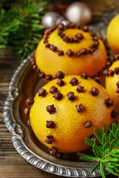 three oranges with chocolate chips on them sitting in a metal bowl next to greenery