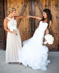 two beautiful women standing next to each other in front of a wooden door holding hands