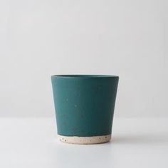 a teal cup with speckles on the outside, sitting on a white surface