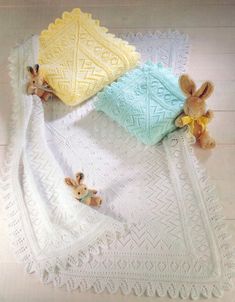 three stuffed animals laying on top of a white crocheted blanket next to each other