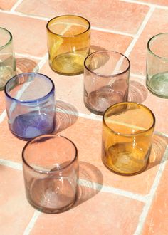 several different colored glasses sitting on top of a tiled floor