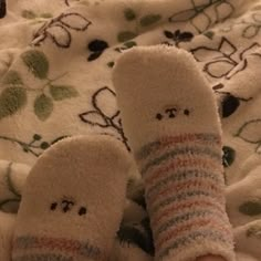 someone is laying down with their feet up on a blanket and wearing socks that have faces drawn on them