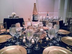 the table is set with gold plates and champagne bottles