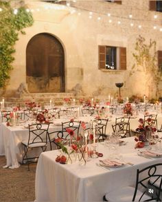 an outdoor dining area with tables and chairs covered in white tablecloths, lit by string lights