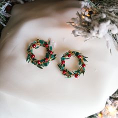 two christmas wreaths sitting on top of a white mannequin